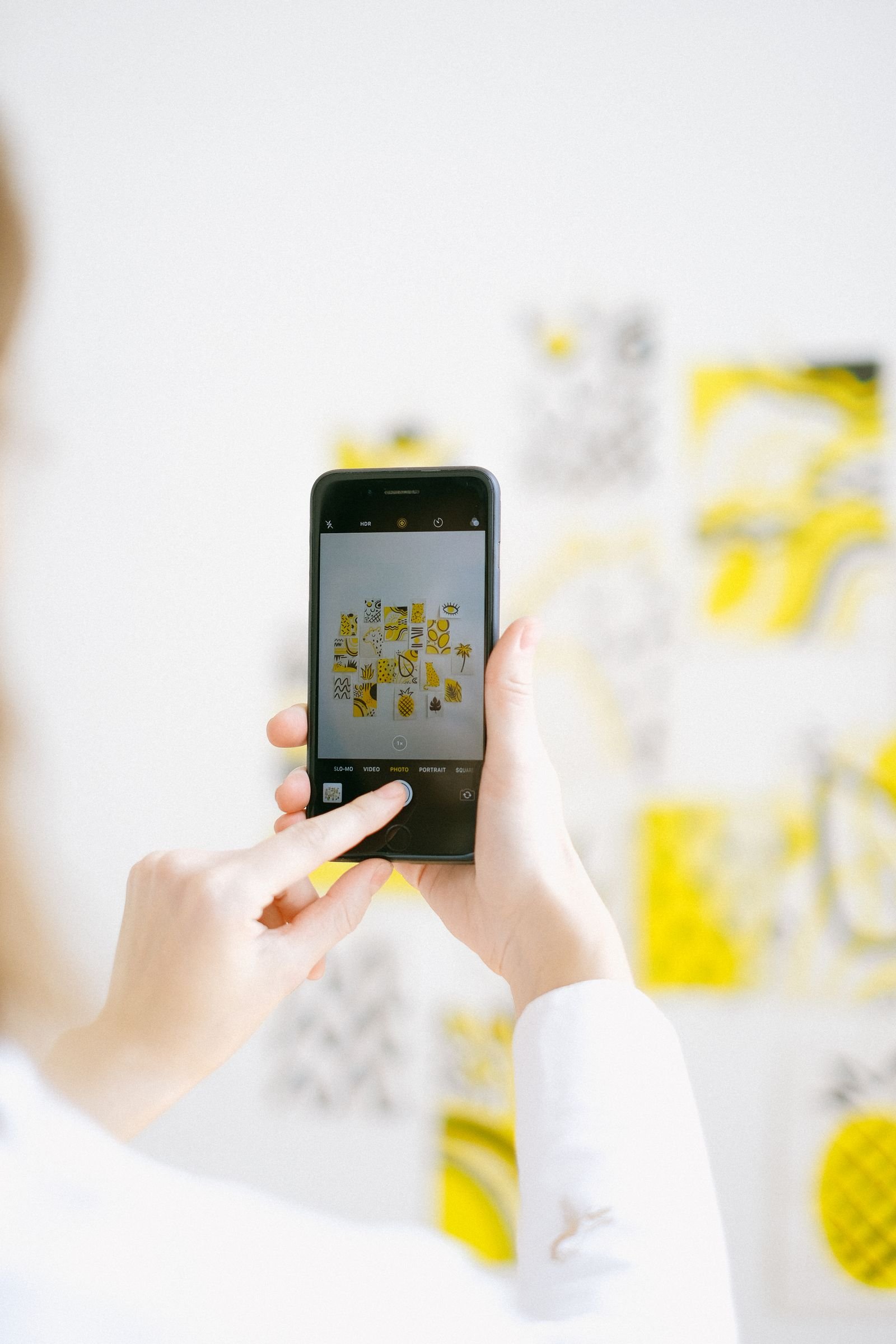 Persona tomando una foto con su celular a una obra de arte colorida