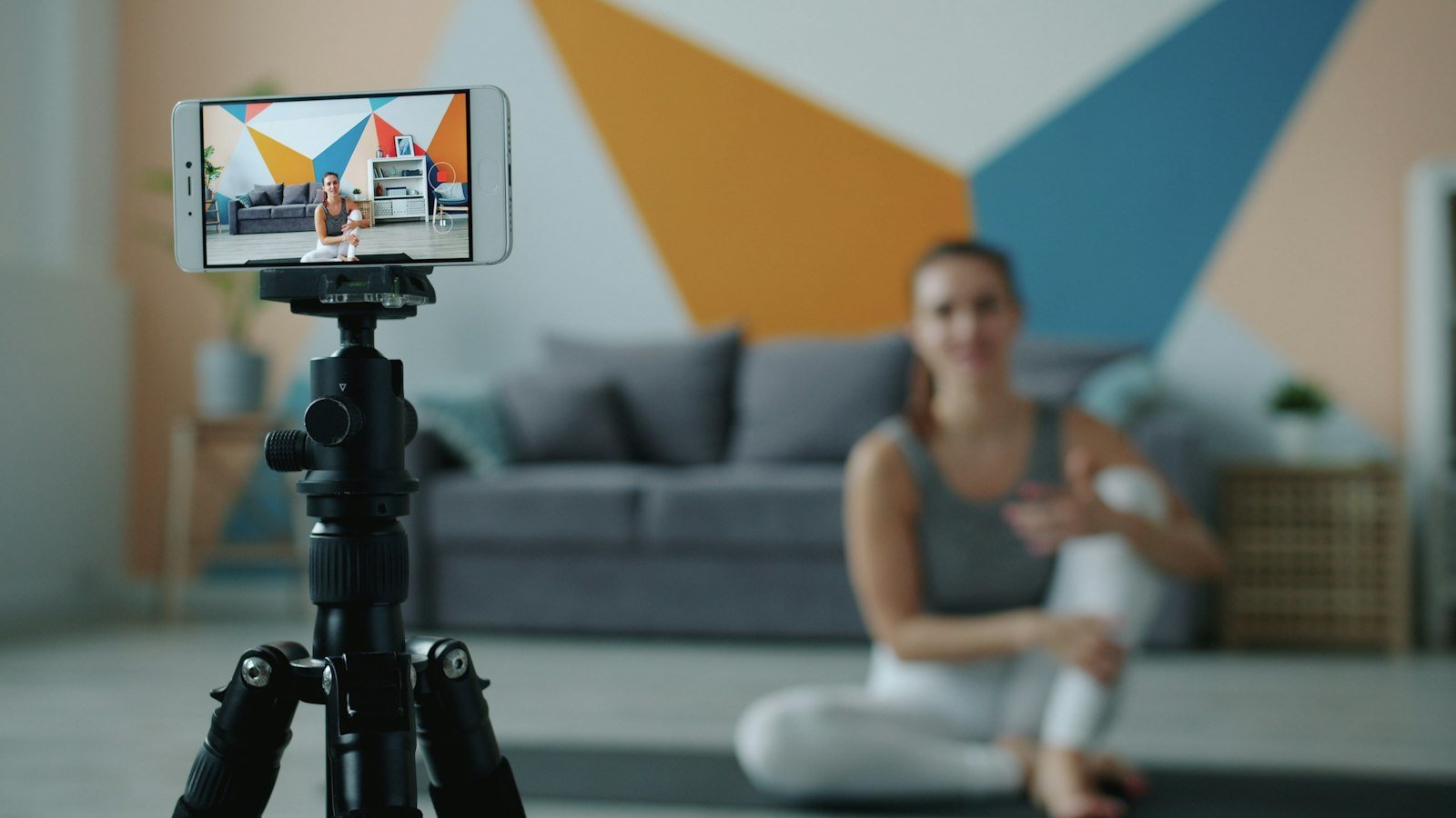 Creadora grabando un video con un celular montado en un tripie dentro de su casa