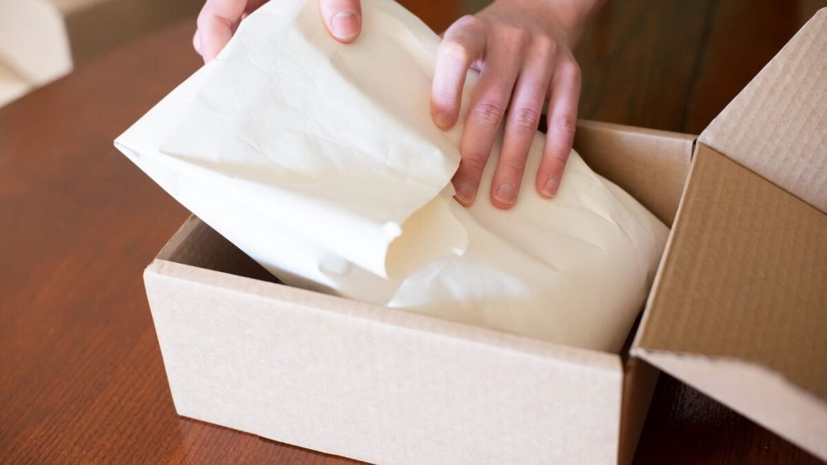 Manos empacando un pedido en una caja de cartón para enviarlo a un cliente